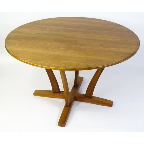 1634 - Vintage / Retro: A teak dining table with a circular top raised on four shaped supports with an x-fr... 