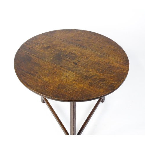 1441 - A 19thC oak cricket table with a circular top above three straight legs united by three stretchers f... 