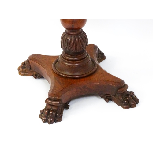 1465 - A 19thC oak tilt top table with a crossbanded top above a turned pedestal with carved acanthus decor... 