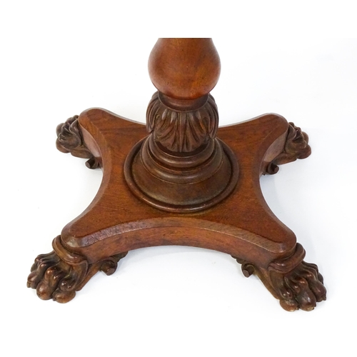 1465 - A 19thC oak tilt top table with a crossbanded top above a turned pedestal with carved acanthus decor... 