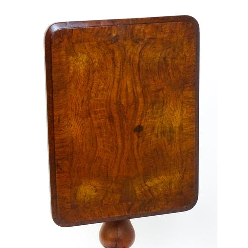 1465 - A 19thC oak tilt top table with a crossbanded top above a turned pedestal with carved acanthus decor... 