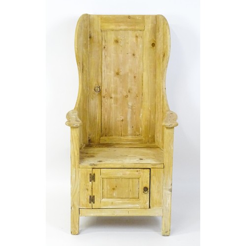 1571 - A pine lambing chair with a wingback above a planked seat and a cupboard to the base with H-bracket ... 