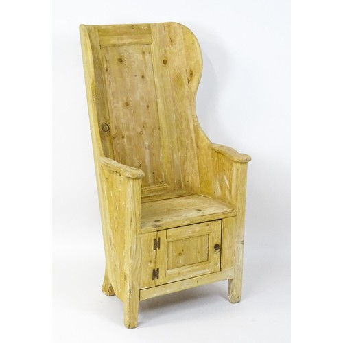 1571 - A pine lambing chair with a wingback above a planked seat and a cupboard to the base with H-bracket ... 