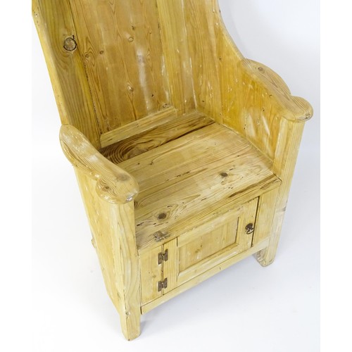 1571 - A pine lambing chair with a wingback above a planked seat and a cupboard to the base with H-bracket ... 