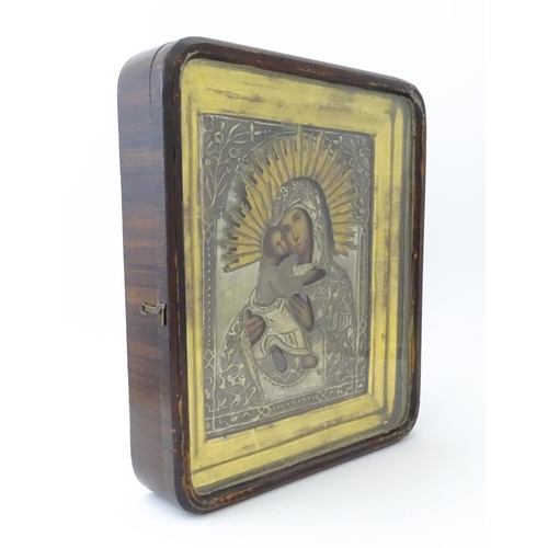 1054 - A 19thC Russian oil on panel icon depicting Madonna and Child with an embossed white metal surround ... 