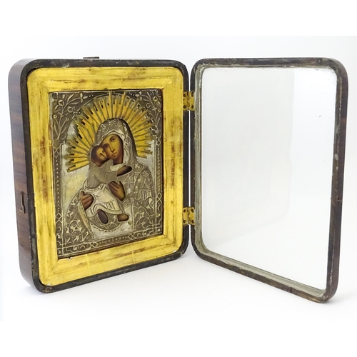 1054 - A 19thC Russian oil on panel icon depicting Madonna and Child with an embossed white metal surround ... 