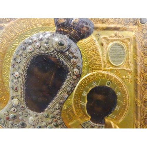 1055 - A 19thC Russian icon depicting Madonna and Child with an embossed gilt metal surround bordered by an... 