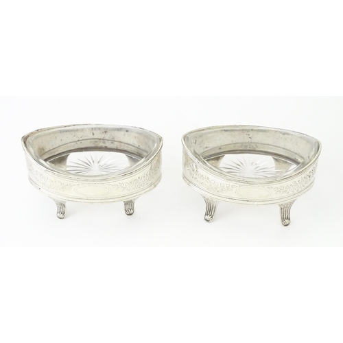 379A - A pair of George IV silver salts with bright cut decoration, and raised on four feet, with clear gla... 