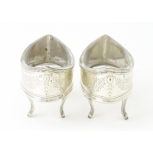 379A - A pair of George IV silver salts with bright cut decoration, and raised on four feet, with clear gla... 