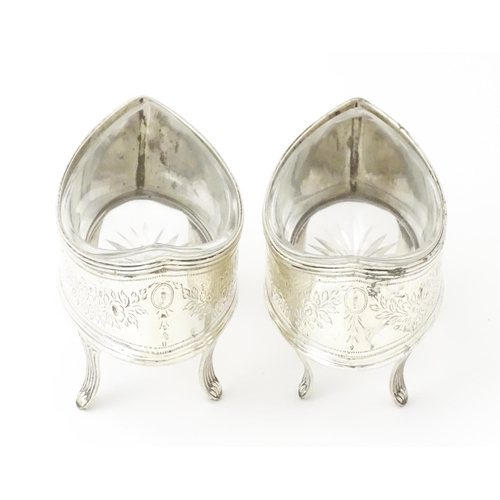 379A - A pair of George IV silver salts with bright cut decoration, and raised on four feet, with clear gla... 