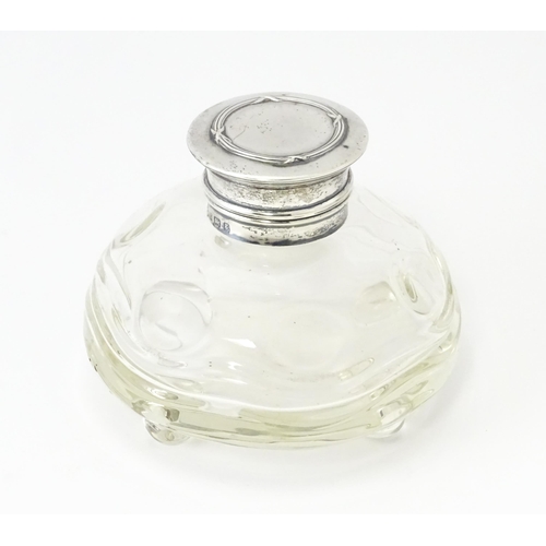 489A - A glass  dressing table scent / perfume bottle raised on four glass bun feet, the silver top hallmar... 