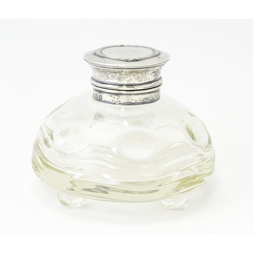 489A - A glass  dressing table scent / perfume bottle raised on four glass bun feet, the silver top hallmar... 