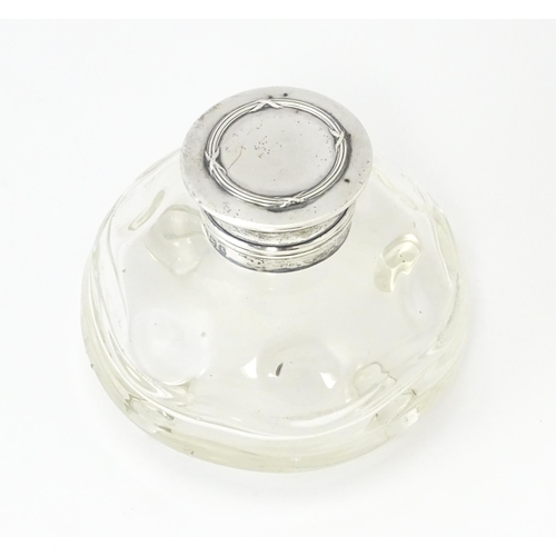 489A - A glass  dressing table scent / perfume bottle raised on four glass bun feet, the silver top hallmar... 