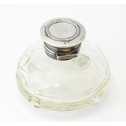 489A - A glass  dressing table scent / perfume bottle raised on four glass bun feet, the silver top hallmar... 