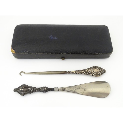 570 - A silver handled button hook hallmarked Chester 1921. Together with a silver handled shoe horn hallm... 