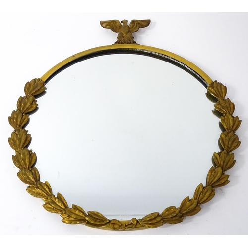 1456 - A 20thC brass wall mirror surmounted by an eagle and with laurel wreath decoration. 26