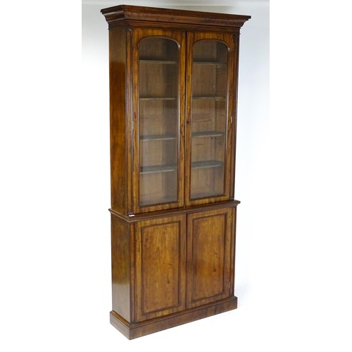 1457 - A 19thC mahogany bookcase with a moulded cornice and two glazed doors with arched panels, the base h... 