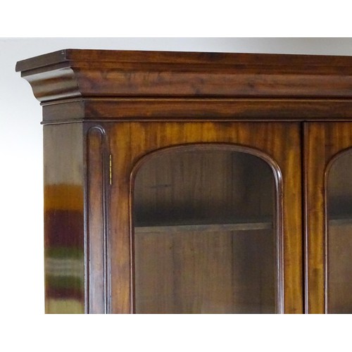 1457 - A 19thC mahogany bookcase with a moulded cornice and two glazed doors with arched panels, the base h... 