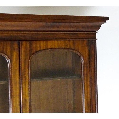 1457 - A 19thC mahogany bookcase with a moulded cornice and two glazed doors with arched panels, the base h... 