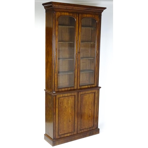 1457 - A 19thC mahogany bookcase with a moulded cornice and two glazed doors with arched panels, the base h... 