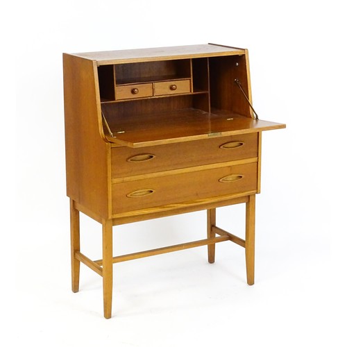 70 - Vintage / Retro: A teak desk, bureau with a fall front above two short drawers raised on four taperi... 