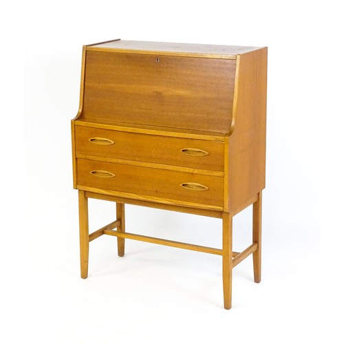 70 - Vintage / Retro: A teak desk, bureau with a fall front above two short drawers raised on four taperi... 