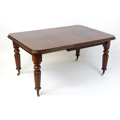 260 - A late 19thC mahogany dining table raised on four turned tapering legs terminating in porcelain cast... 