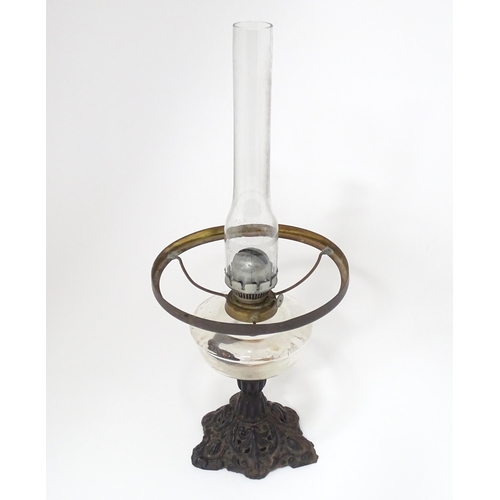 320 - An early 20thC table oil lamp with chimney and shade, the cast iron base supporting a clear glass re... 