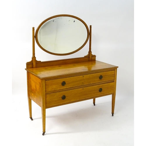 566 - An early 20thC dressing table with an oval mirror above two long drawers and raised on four tapering... 