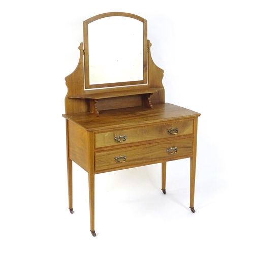 657 - An early 20thC mahogany dressing table with a shaped upstand, shelf and arched mirror. The top havin... 