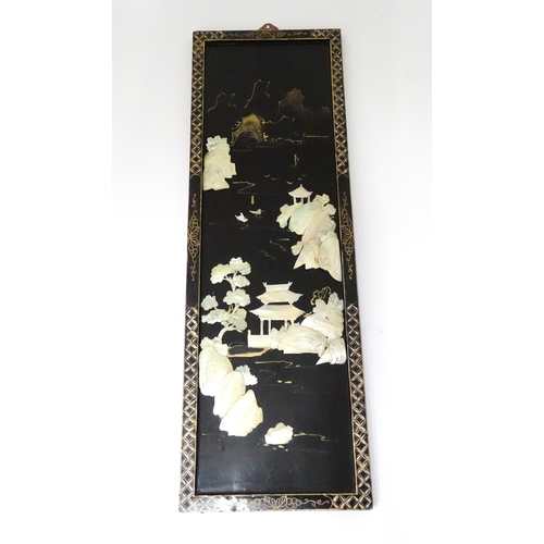 33 - An Oriental lacquered picture with applied abalone detail depicting a river with pagoda style buildi... 