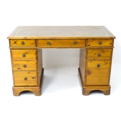 32 - A late 20thC Ducal pine one-piece pedestal desk, the top with brown leather insert and three drawers... 