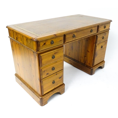 32 - A late 20thC Ducal pine one-piece pedestal desk, the top with brown leather insert and three drawers... 