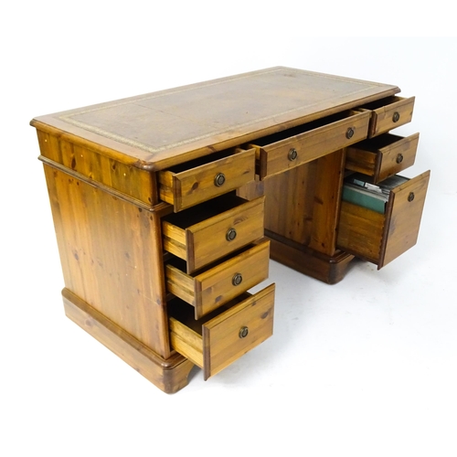 32 - A late 20thC Ducal pine one-piece pedestal desk, the top with brown leather insert and three drawers... 