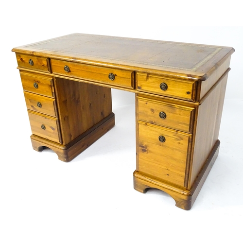 32 - A late 20thC Ducal pine one-piece pedestal desk, the top with brown leather insert and three drawers... 