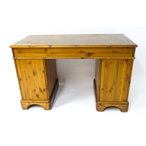 32 - A late 20thC Ducal pine one-piece pedestal desk, the top with brown leather insert and three drawers... 