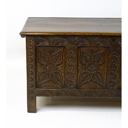 6 - An 18thC oak coffer with a hinged lid above four carved floral panels raise on stile feet. 59