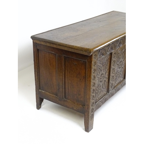 6 - An 18thC oak coffer with a hinged lid above four carved floral panels raise on stile feet. 59