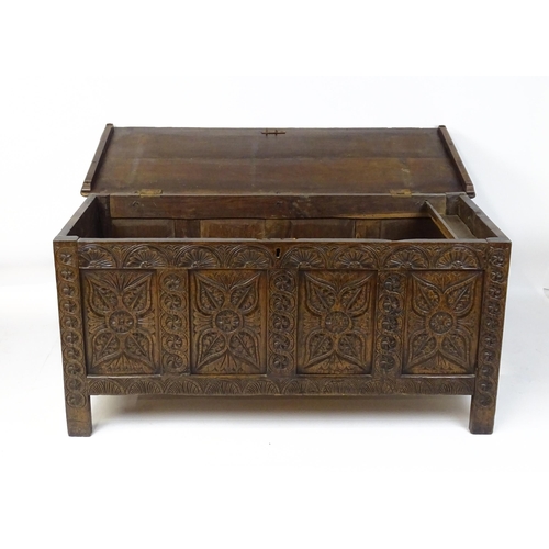 6 - An 18thC oak coffer with a hinged lid above four carved floral panels raise on stile feet. 59