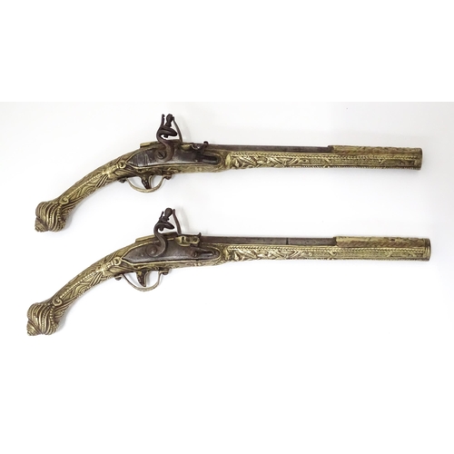 343 - A pair of mid 20thC decorative / display Eastern flintlock pistols, each constructed from brass with... 