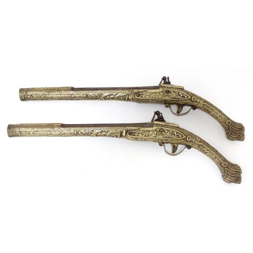 343 - A pair of mid 20thC decorative / display Eastern flintlock pistols, each constructed from brass with... 