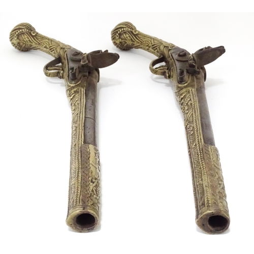 343 - A pair of mid 20thC decorative / display Eastern flintlock pistols, each constructed from brass with... 