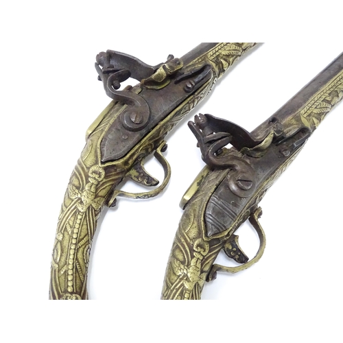 343 - A pair of mid 20thC decorative / display Eastern flintlock pistols, each constructed from brass with... 