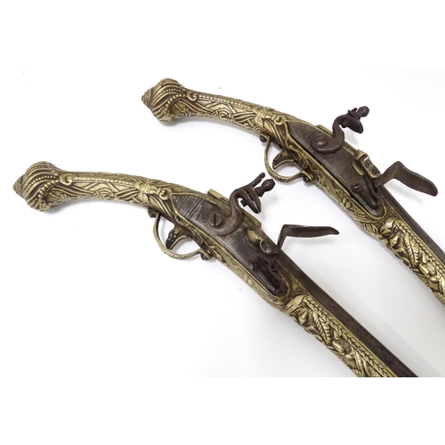 343 - A pair of mid 20thC decorative / display Eastern flintlock pistols, each constructed from brass with... 