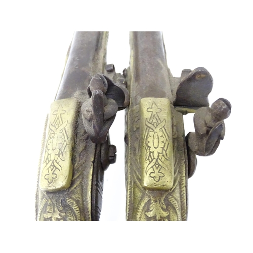 343 - A pair of mid 20thC decorative / display Eastern flintlock pistols, each constructed from brass with... 