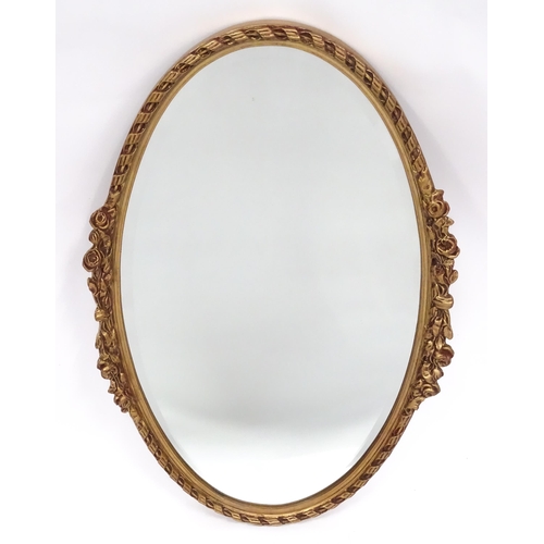 13 - A late 20thC wall mirror, of oval form with bevelled glass, the gilt frame decorated with rope twist... 