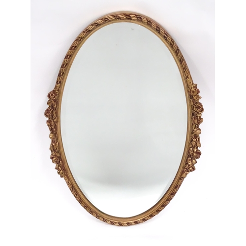 13 - A late 20thC wall mirror, of oval form with bevelled glass, the gilt frame decorated with rope twist... 