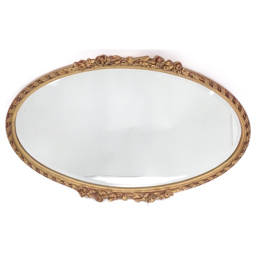 13 - A late 20thC wall mirror, of oval form with bevelled glass, the gilt frame decorated with rope twist... 