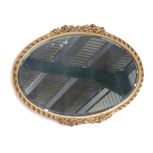 13 - A late 20thC wall mirror, of oval form with bevelled glass, the gilt frame decorated with rope twist... 