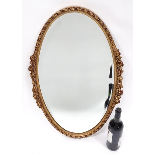 13 - A late 20thC wall mirror, of oval form with bevelled glass, the gilt frame decorated with rope twist... 